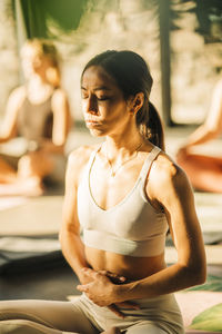 Young woman with hands on stomach practicing yoga at retreat center