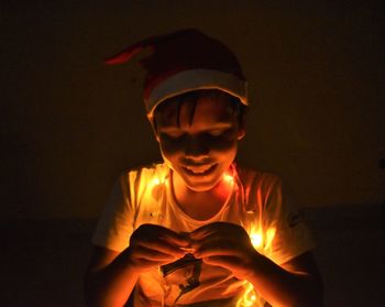 Portrait of boy holding lit candle in the dark