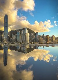 Reflection of buildings in lake against sky during sunset