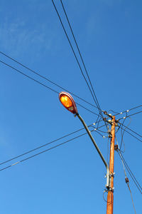 Low angle view of electricity pylon against clear blue sky