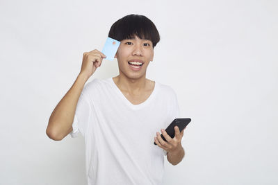 Portrait of smiling man using smart phone against white background