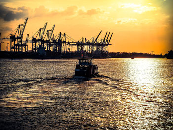 Boat sailing in elbe river at port of hamburg during sunset