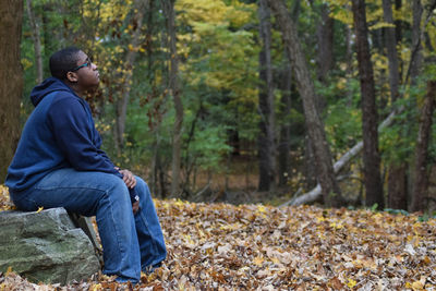 Side view of man sitting on rock at park