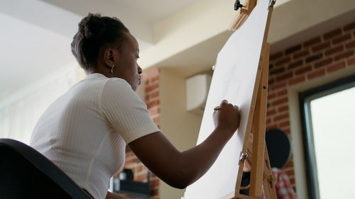 Low angle view of woman drawing on canvas