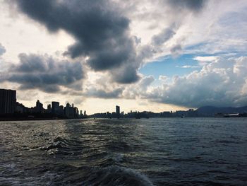 Sea by cityscape against sky