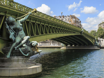 Statue of bridge over river against sky