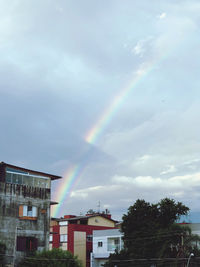 Low angle view of rainbow over buildings against sky