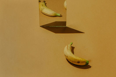 High angle view of banana with mirror on yellow background