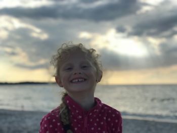Portrait of smiling girl at beach against sky