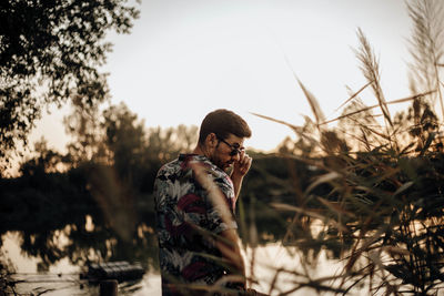 Boy looking interested in something through his sunglasses at sunset