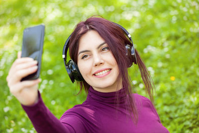 Portrait of a smiling young woman using phone outdoors