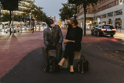 Businessman discussing with female colleague in city during covid-19