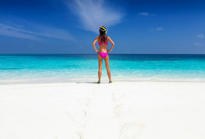 Rear view of young woman wearing bikini at beach on sunny day