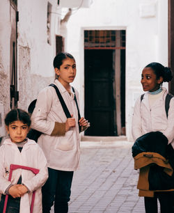 Full length of friends standing against wall