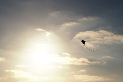 Low angle view of silhouette kite flying against sky