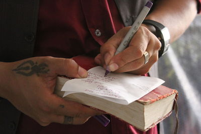 Midsection of man reading book on paper