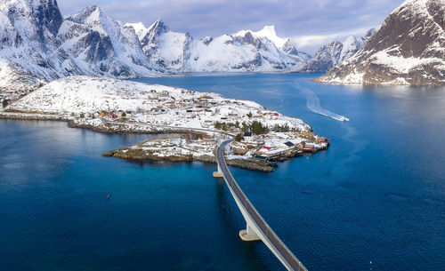 Scenic view of sea by snowcapped mountains against sky