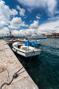 Fishing boats moored at harbor against sky