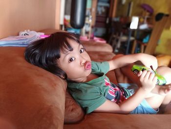 Portrait of girl puckering lips while lying on sofa at home