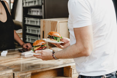 Man holds in his hand burgers at a burger feast. dinner hamburger food feast party. big burger in