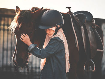 Girl standing by horse