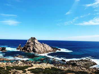 Scenic view of rocks in sea against blue sky