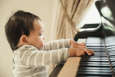 Cute boy playing piano at home