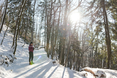 Woman standing on snow covered field in forest