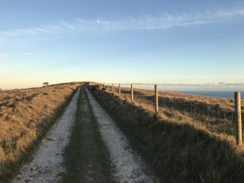 Road amidst field against sky