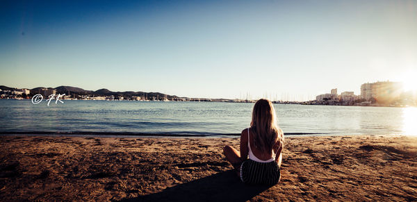 Rear view of woman looking at sea against clear sky