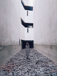 Rear view of woman standing on footpath against building