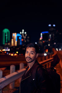 Portrait of young man standing in city at night