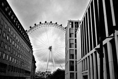 Low angle view of ferris wheel against buildings in city