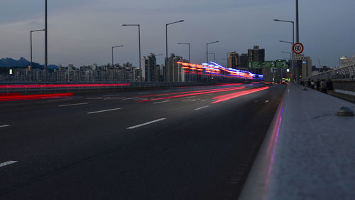 Light trails on city street against sky