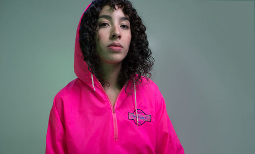 Portrait of beautiful young woman standing against pink background