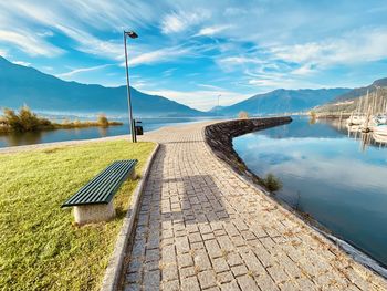 Footpath by lake against sky