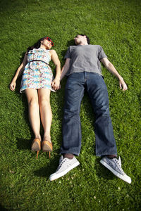 High angle view of couple lying on grassy field