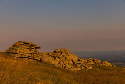 Rock formations on landscape against sky during sunset