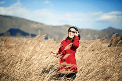 Woman standing on field against cloudy sky