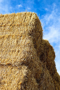 Low angle view of hay bales on field against sky