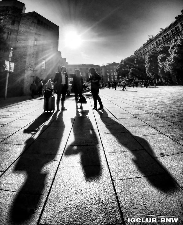 sunlight, lifestyles, sunbeam, sun, shadow, walking, men, building exterior, leisure activity, lens flare, architecture, person, sunny, built structure, large group of people, street, full length, city, city life