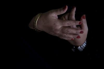 Cropped hands of man and woman against black background