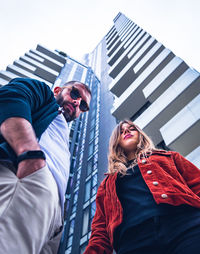 Low angle view of friends standing against sky