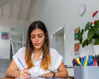 Young woman looking away while sitting on table