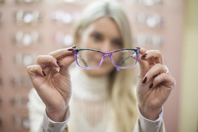 Blond woman selecting new glasses in opticians shop