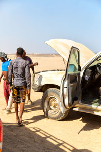 Rear view of men on car against sky