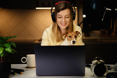 Woman and dog using laptop at night