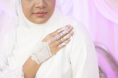 Midsection of woman with arms raised against white background
