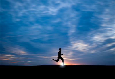 Silhouette man running against cloudy sky during sunset