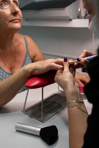 Senior woman in cosmetic salon doing manicure with specialist